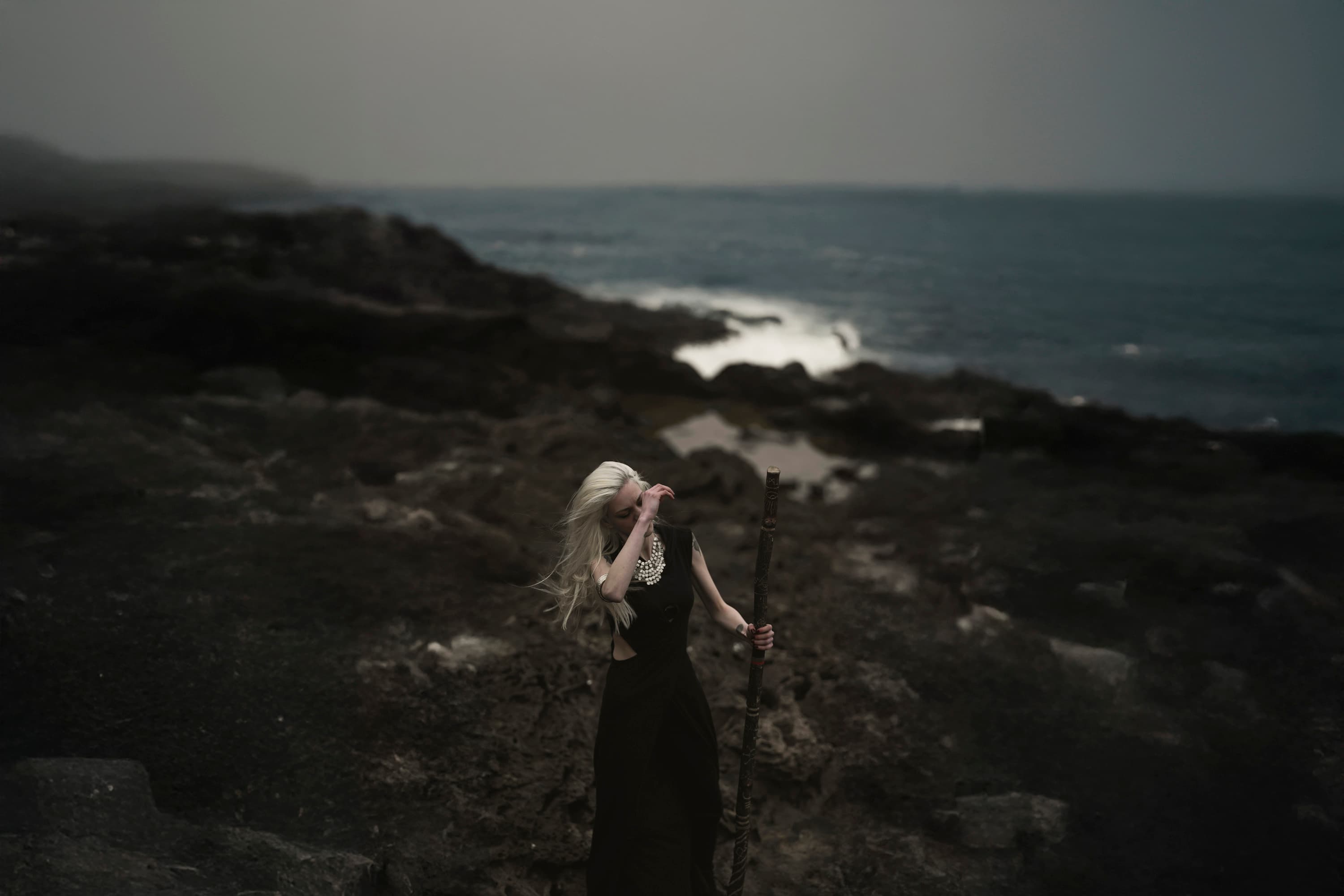 A figure among dark rocks beside the sea